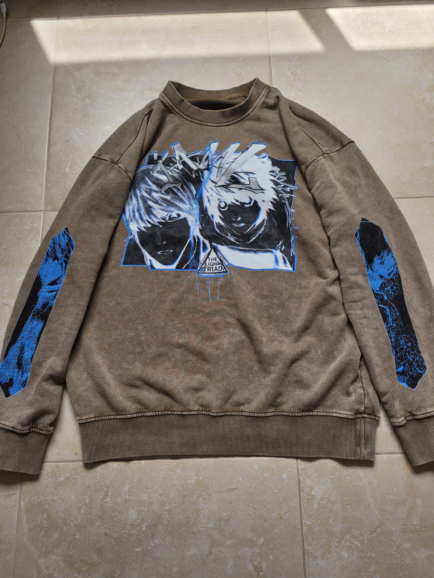 Brown sweatshirt with graphic design on a tiled floor